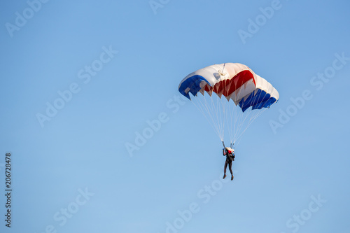 isolated skydiver control colorful parachute gliding after free fall jump with blue sky background