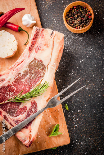 Raw beef marbled meat striplon rib eye steak with spices, herbs, dark background, copy space photo