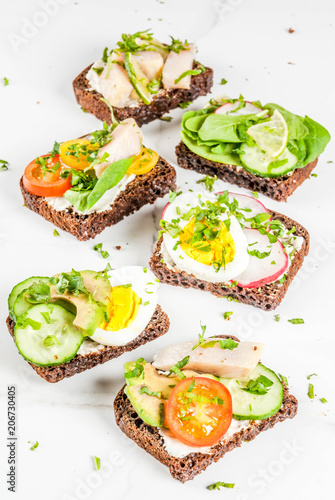 Set of various danish open sandwiches Smorrebrod with fish, egg and fresh vegetables, white marble background copy space