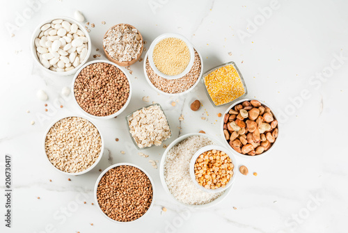Φωτογραφία Selection various types cereal grains groats  in different bowl on white marble
