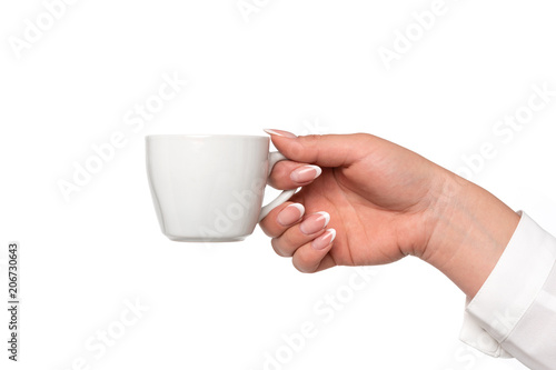 Beautiful and perfect female hand holding a white porcelain cup isolated on a white background in close-up