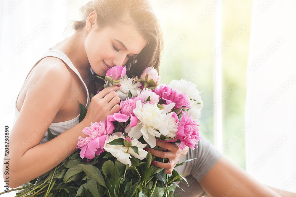 Very beautiful young woman with flowers. Portrait of attractive girl with peonies