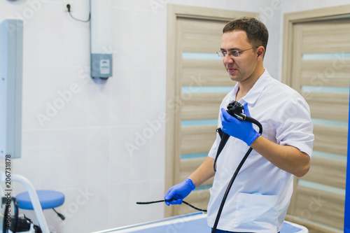 Proctologist holding an anoscope against a proctological chair. In the hospital photo