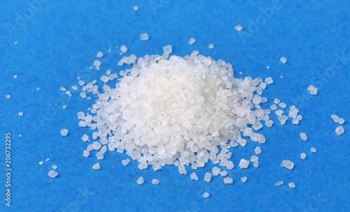 Pile of sugar isolated on blue background, closeup