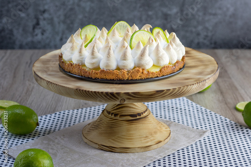 Lime meringue cake on wooden plate with slices of lime