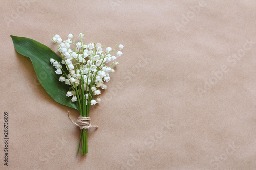 Bouquet of lilies of the valley on the brown kraft paper background