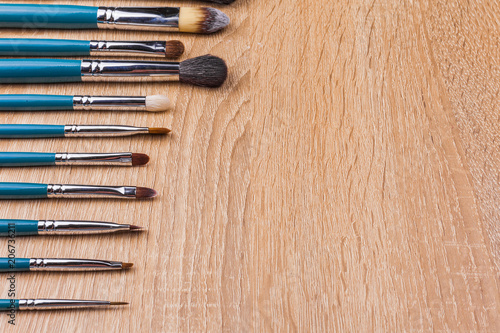 row of brushes in blue coating different in shapes and in use. tools laying on the wooden background. concept of professional cosmetics. free space for text