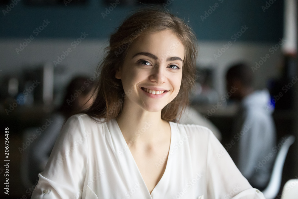 Smiling young pretty lady looking at camera in public place, adolescent girl with cute pretty face posing indoors, happy millennial casual woman student or professional in cafe head shot portrait Smiling young pretty lady looking at camera in public place, adolescent girl with cute pretty face posing indoors, happy millennial casual woman student or professional in cafe head shot portrait