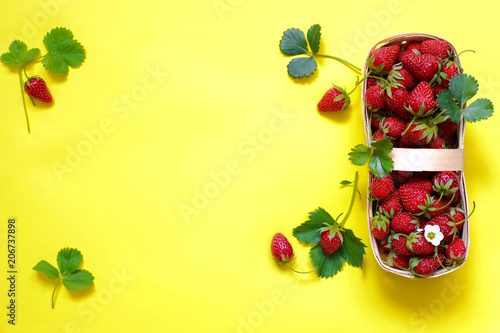 Fototapeta Naklejka Na Ścianę i Meble -  basket with fresh strawberries on a yellow background top view