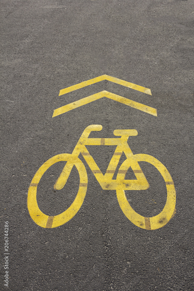 Yellow sign of a bicycle path drawn on the asphalt road. Lanes for cyclists. Cyclist on urban cycleway. Traffic signs and road safety. Yellow sign of a bicycle path drawn on the asphalt road. Lanes for cyclists. Cyclist on urban cycleway. Traffic signs and road safety.