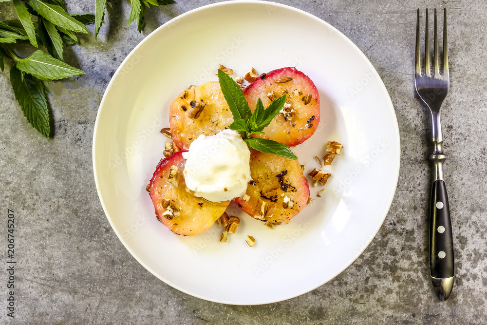 Baked peaches with ice cream on a plate on a gray metal background Baked peaches with ice cream on a plate on a gray metal background