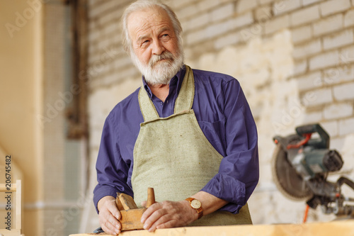 Photos close up portrait of hardworking handyman using a planer at work