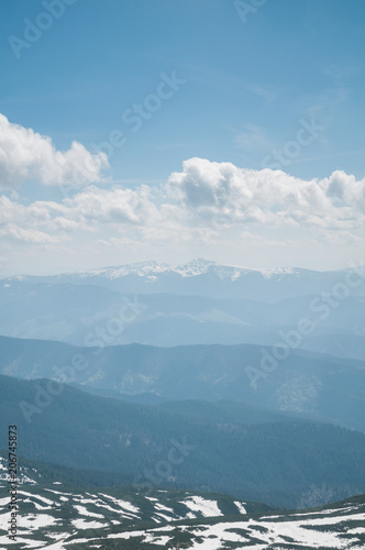 A beautiful view of the snow-capped mountains of the Carpathians from the top of Goverly in spring in a beautiful sunny day with light clouds. Carpathians, Goverla, Ukraine.