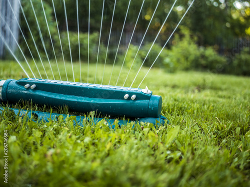 close up automatic system of water splinker pouring green lawn in the garden photo