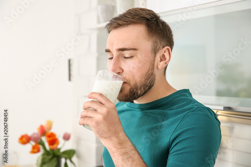 Young man drinking tasty milk at home