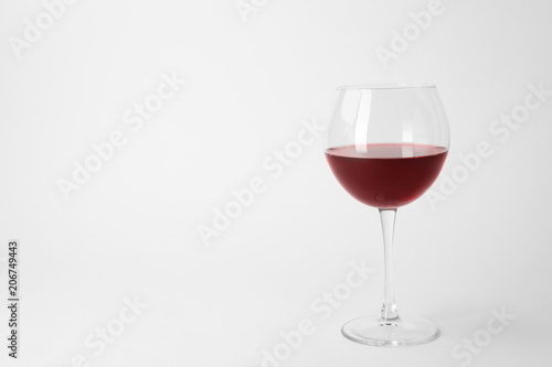 Glass of expensive red wine on light background