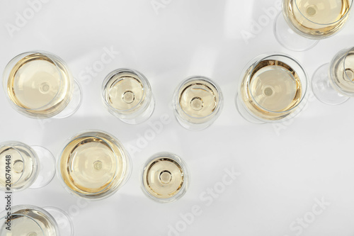 Glass of expensive white wine on light background, top view