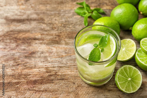 Refreshing lime beverage and ingredients on wooden background