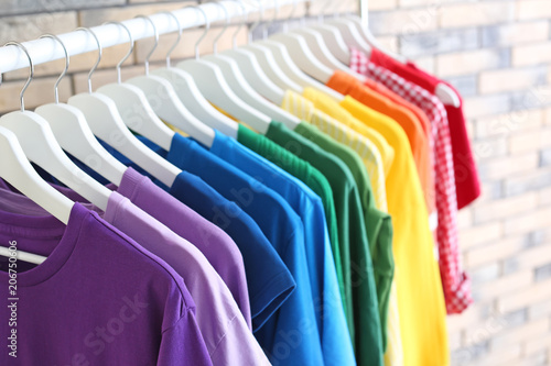 Rack with rainbow clothes on brick wall background