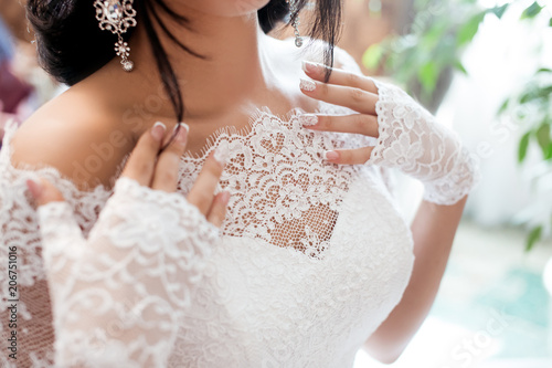 beautiful bride in a white dress and veil with a hairdress and flowers hands in gloves, nipple shoulder décolletage