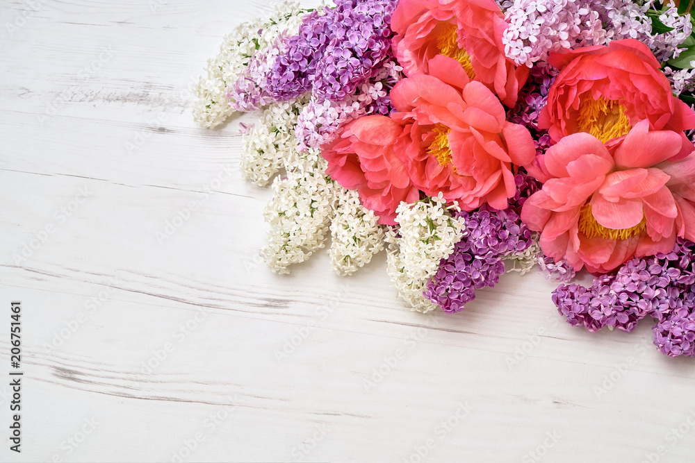 Peonies and lilac flowers on white wooden background. Top view, copy space. Holiday background. Peonies and lilac flowers on white wooden background. Top view, copy space. Holiday background.