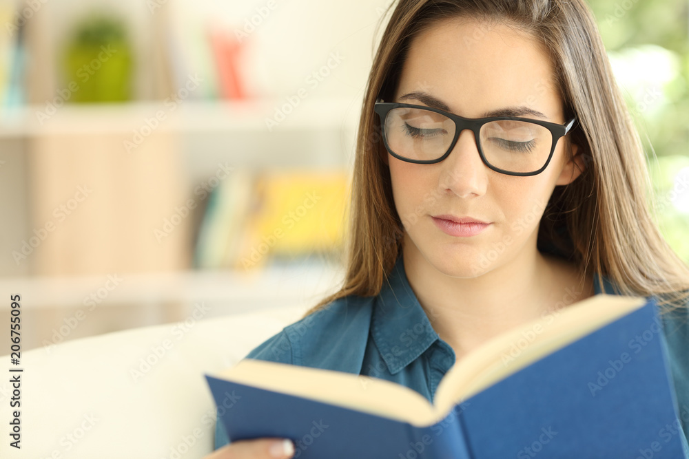 Serious woman wearing eyeglasses reading a paper book Serious woman wearing eyeglasses reading a paper book