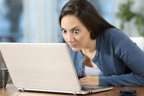 Schilderij op canvas Perplexed woman reading online news in a laptop