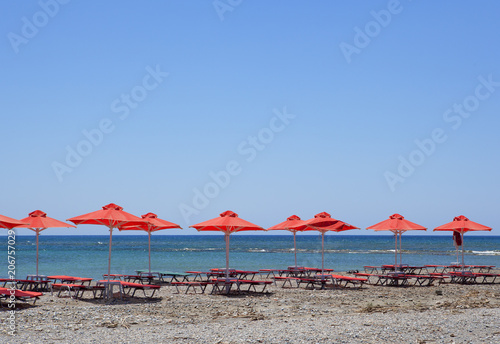 Line of red sea sunshades at beach in summer day © ALLA
