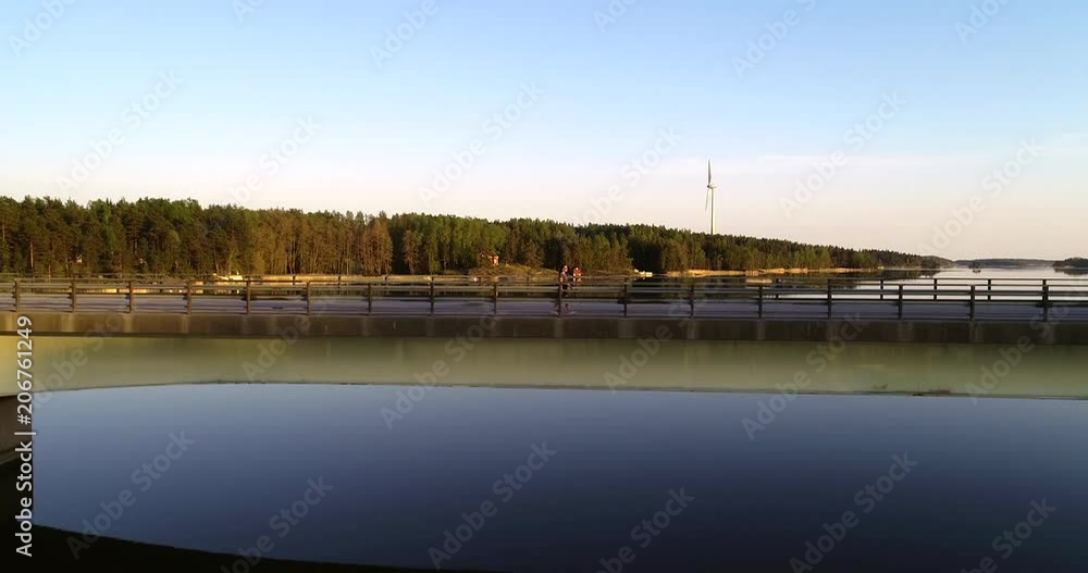 Woman walking in saaristo, C4k aerial view tracking a girl on a island bridge, in the finnish archipelago, on the gulf of finland, on a calm summer evening dawn, in Inkoo, Uusimaa, Woman walking in saaristo, C4k aerial view tracking a girl on a island bridge, in the finnish archipelago, on the gulf of finland, on a calm summer evening dawn, in Inkoo, Uusimaa,