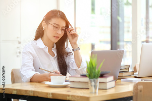 Portrait of attractive young asian woman sitting at home office in front of her laptop