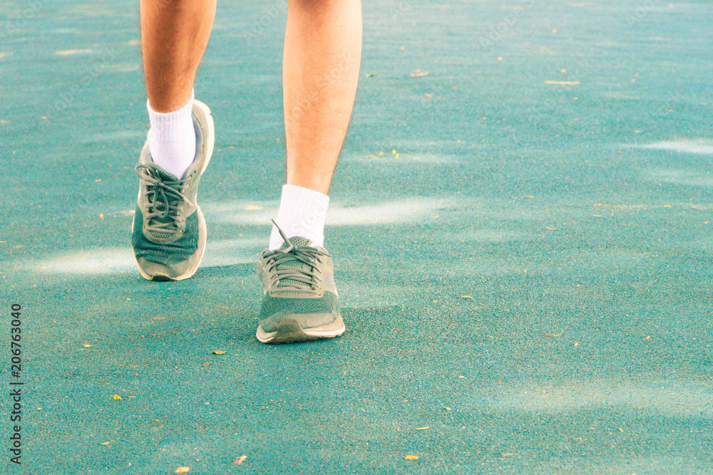 running feet male in runner jogging exercise with old shoes for health lose weight concept on track rubber cover blue public park. copy space add text running feet male in runner jogging exercise with old shoes for health lose weight concept on track rubber cover blue public park. copy space add text