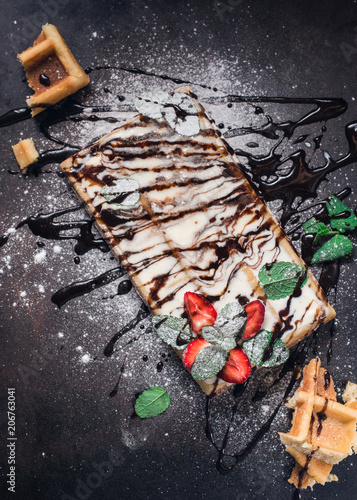 Belgium waffles with chocolate sauce, ice cream and strawberries isolated on black background