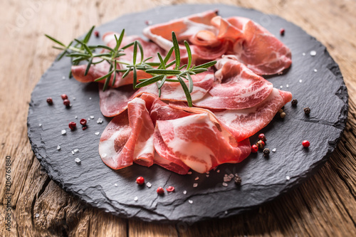 Coppa di Parma ham on slate board with rosemary salt and pepper