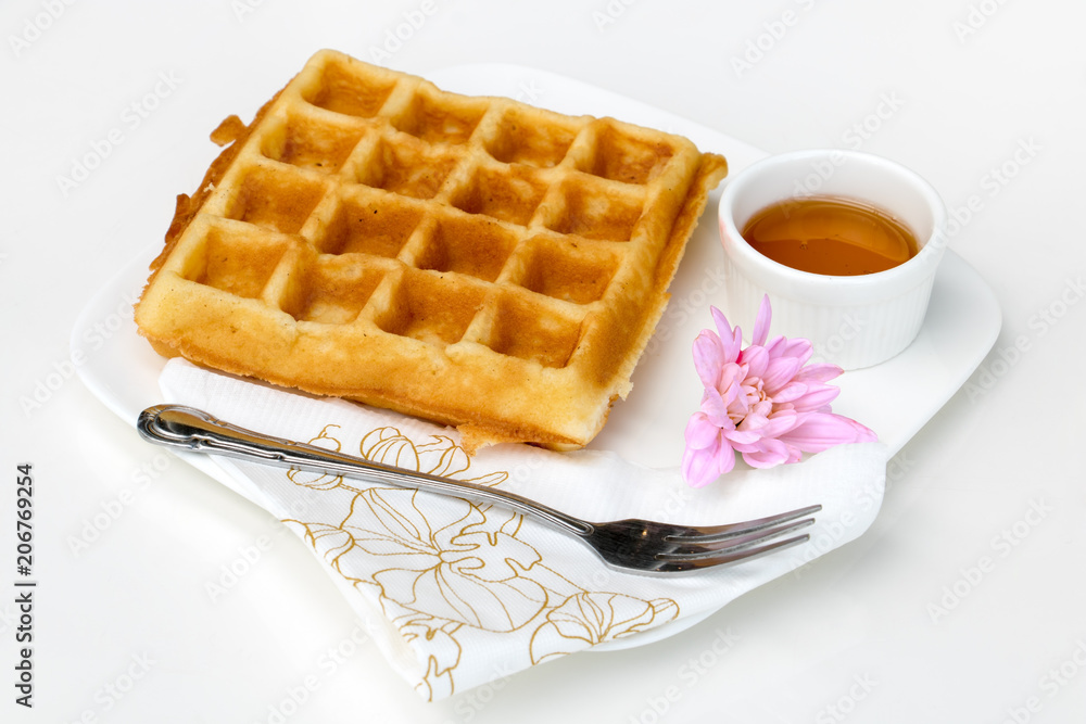 Waffle with honey on white table.Fresh homemade waffles serving on a plate with blossom and honey. Romantic breakfast. Waffle with honey on white table.Fresh homemade waffles serving on a plate with blossom and honey. Romantic breakfast.