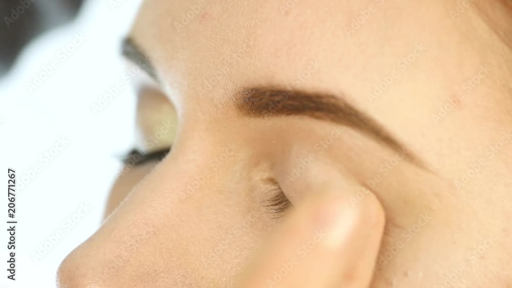 Close-up make-up artist hand, applying eyeshadow to woman's eye using fingers. Close-up make-up artist hand, applying eyeshadow to woman's eye using fingers.