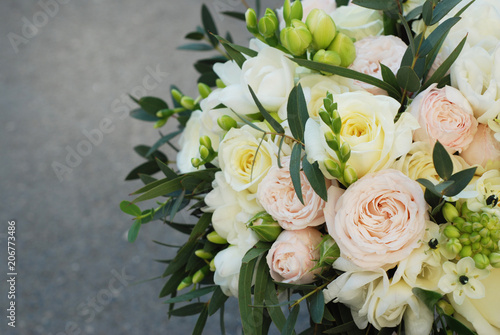 White Wedding Bouquet Roses Pink flowers and Ruscus Leaves with Robbons on Gray Asphalt Background. Wedding Decoration