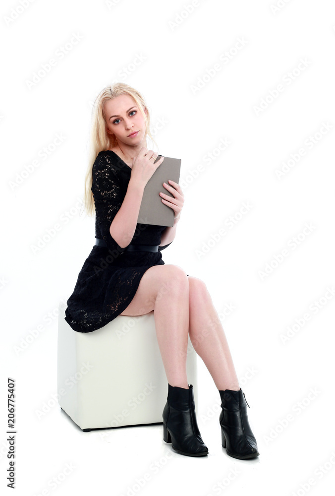 full length portrait of girl wearing black dress, sitting pose on ottoman.  isolated on white studio background. Stock Photo | Adobe Stock