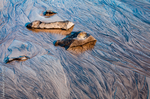 Icelandic sand beach details with stones at warm sunset photo