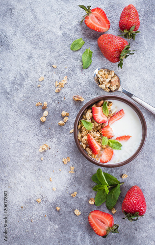 Breakfast Food. Bowl with yogurt, granola of muesli and strawberries on gray concrete table background. Healthy Vegan Clean Diet Food Concept. Top view, copy space, flat lay