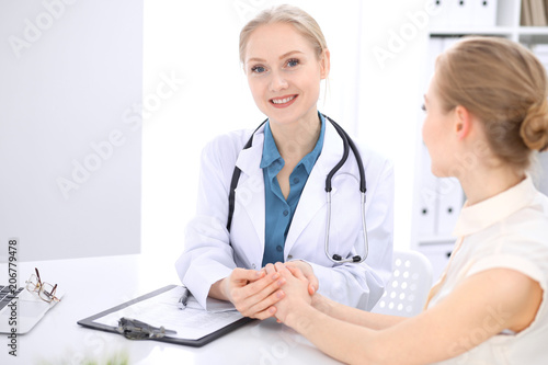 Blonde female doctor and patient talking in hospital office. Health care and client service in medicine