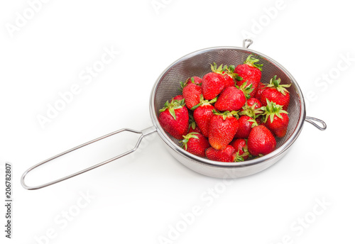 Washed strawberries in stainless steel sieve on a white background