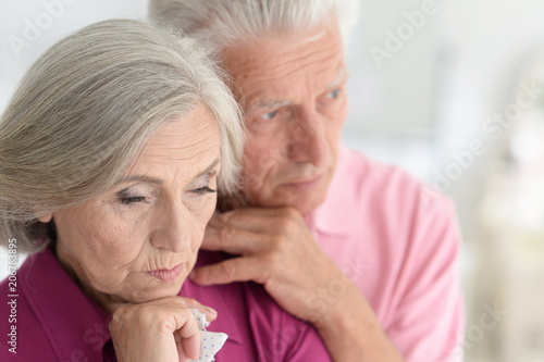 Sad Senior couple at home hugging 