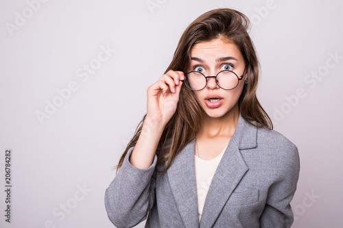 Wow. I don't believe you. Close up portrait of shocked astonished woman with open mouth and big eyes, she is touching her spectacles