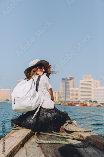 Young beautiful woman sitting at boat and looking at sea and the city DUbai © Tetiana