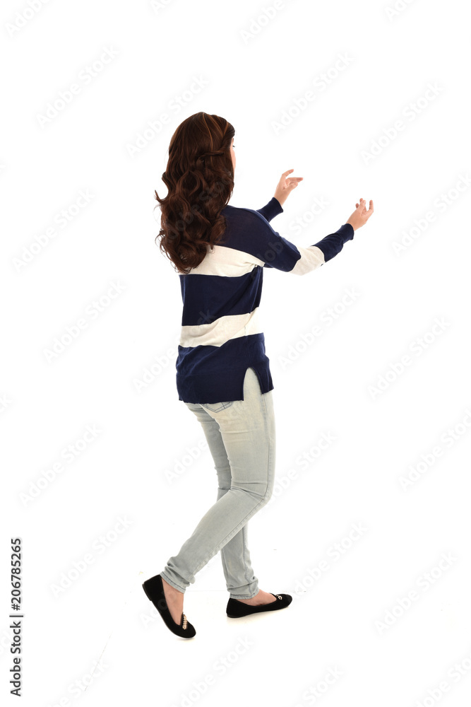 full length portrait of girl wearing striped blue and white jumper and jeans. standing pose facing away from the camera, on white studio background full length portrait of girl wearing striped blue and white jumper and jeans. standing pose facing away from the camera, on white studio background