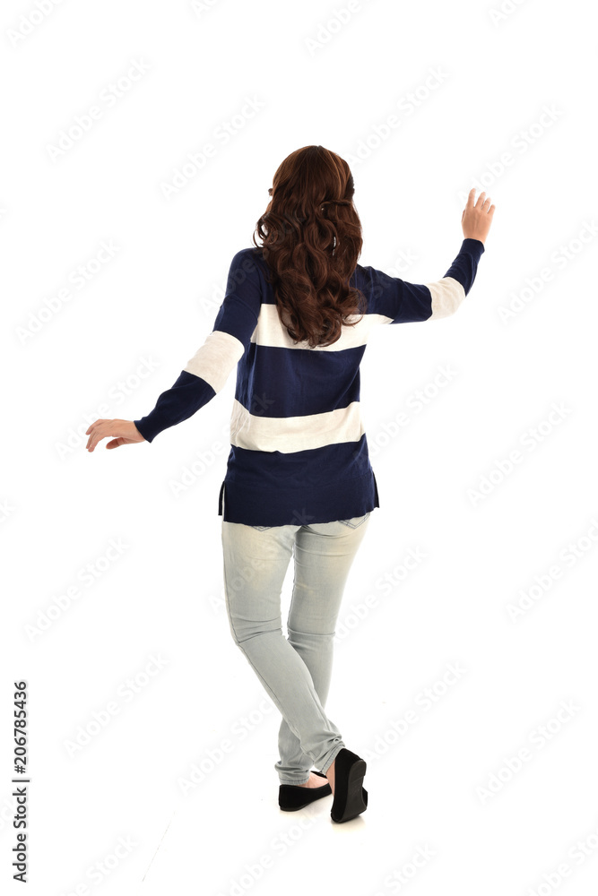 full length portrait of girl wearing striped blue and white jumper and jeans. standing pose facing away from the camera, on white studio background full length portrait of girl wearing striped blue and white jumper and jeans. standing pose facing away from the camera, on white studio background