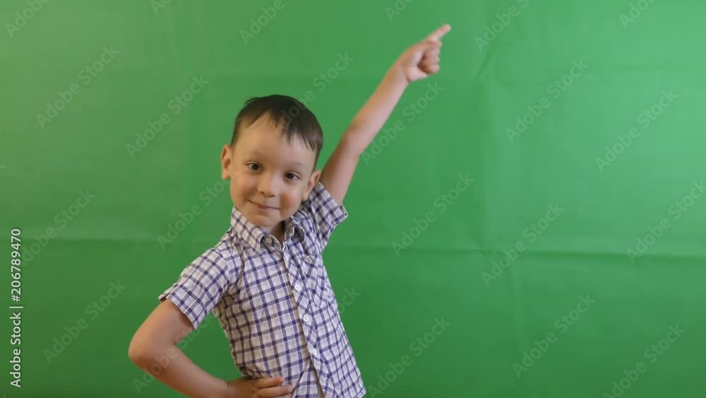Little boy standing in front of a green background while folded hands and showing thumbs up. Shot over green screen. Little boy standing in front of a green background while folded hands and showing thumbs up. Shot over green screen.