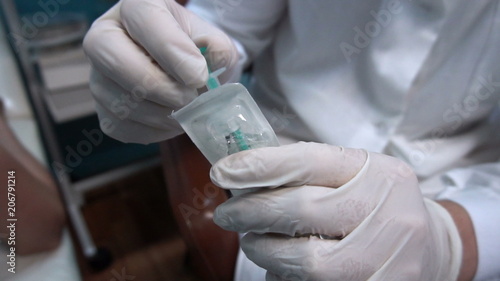 the doctor pulls out the syringe from the packaging.