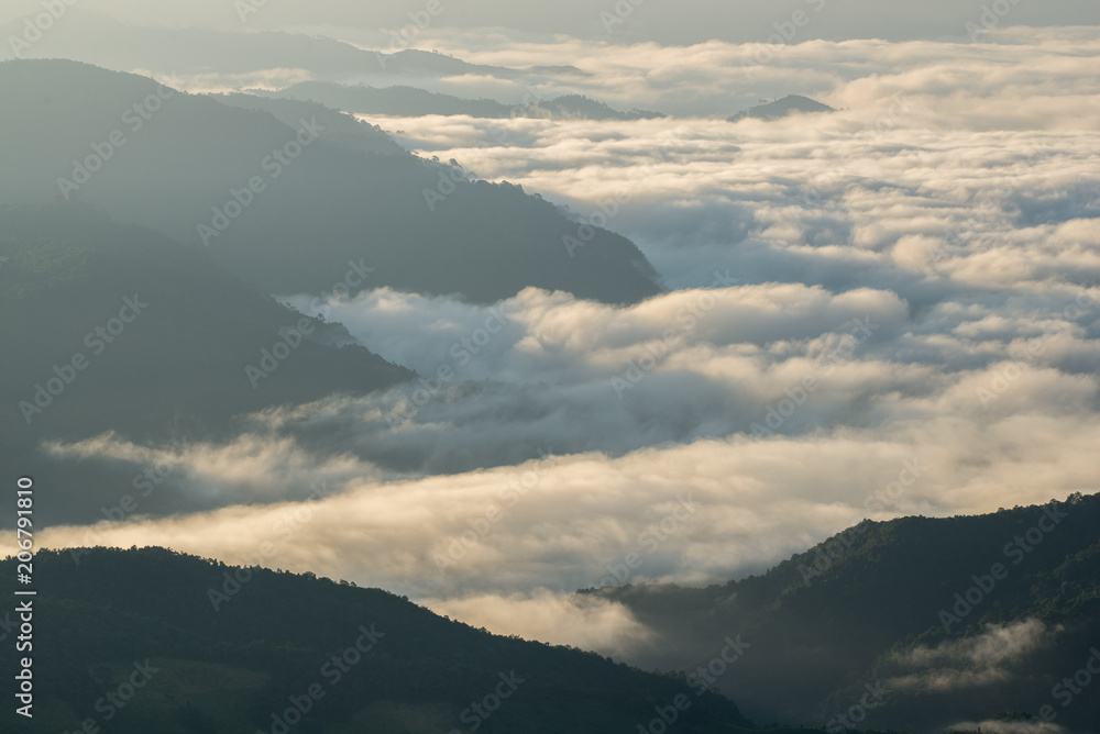 Mountain silhouette above the clouds at sunrise, view from the top view of mountains.