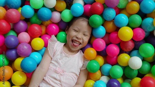 Happy asian girl playing in colorful balls pool